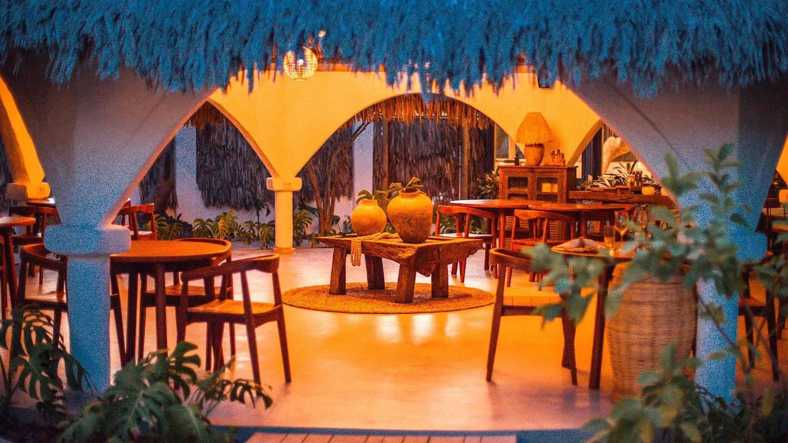 Mesas do restaurante sob teto de palha azul